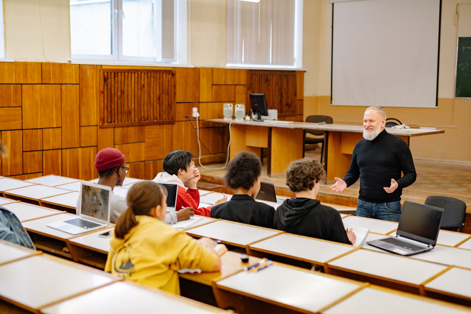 Teacher using laptop in a bright classroom to prepare a lesson plan with AI software