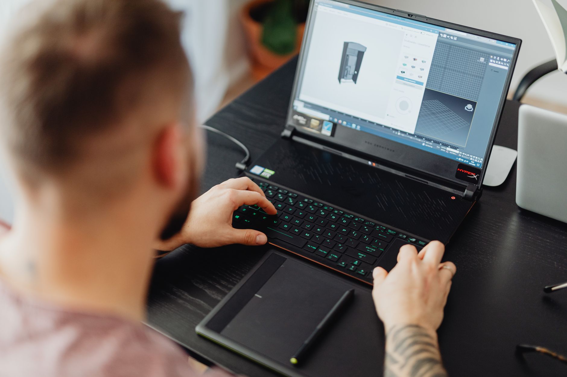 A smartphone photo of a shoe next to a laptop showing a 3D model.